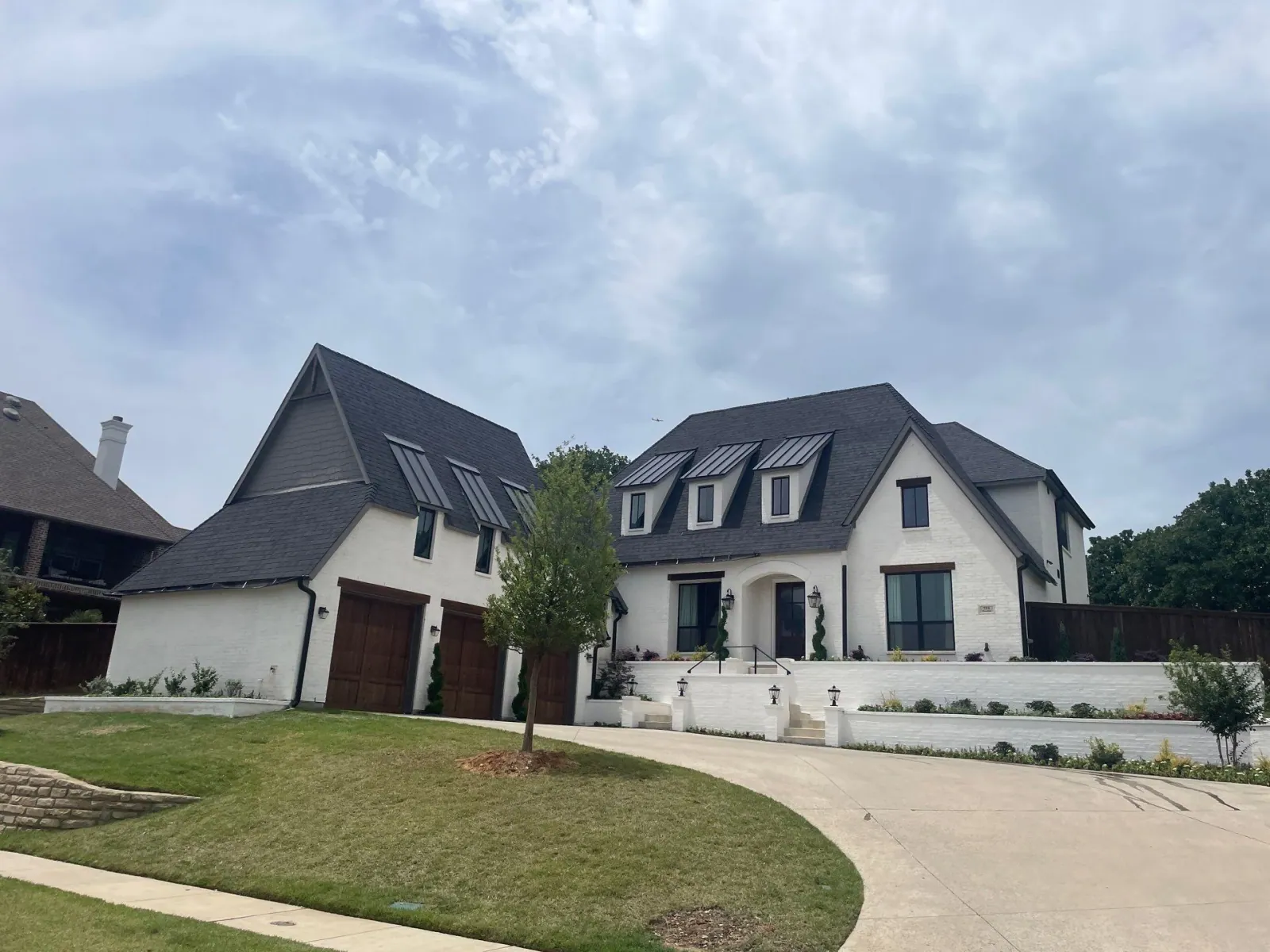 A finished home exterior with a new charcoal shingle roof, clean siding, gutters, and trim