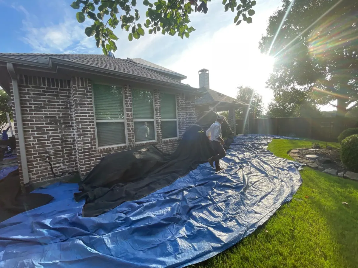 A crew protecting a homeowner's yard with tarps during a roof job